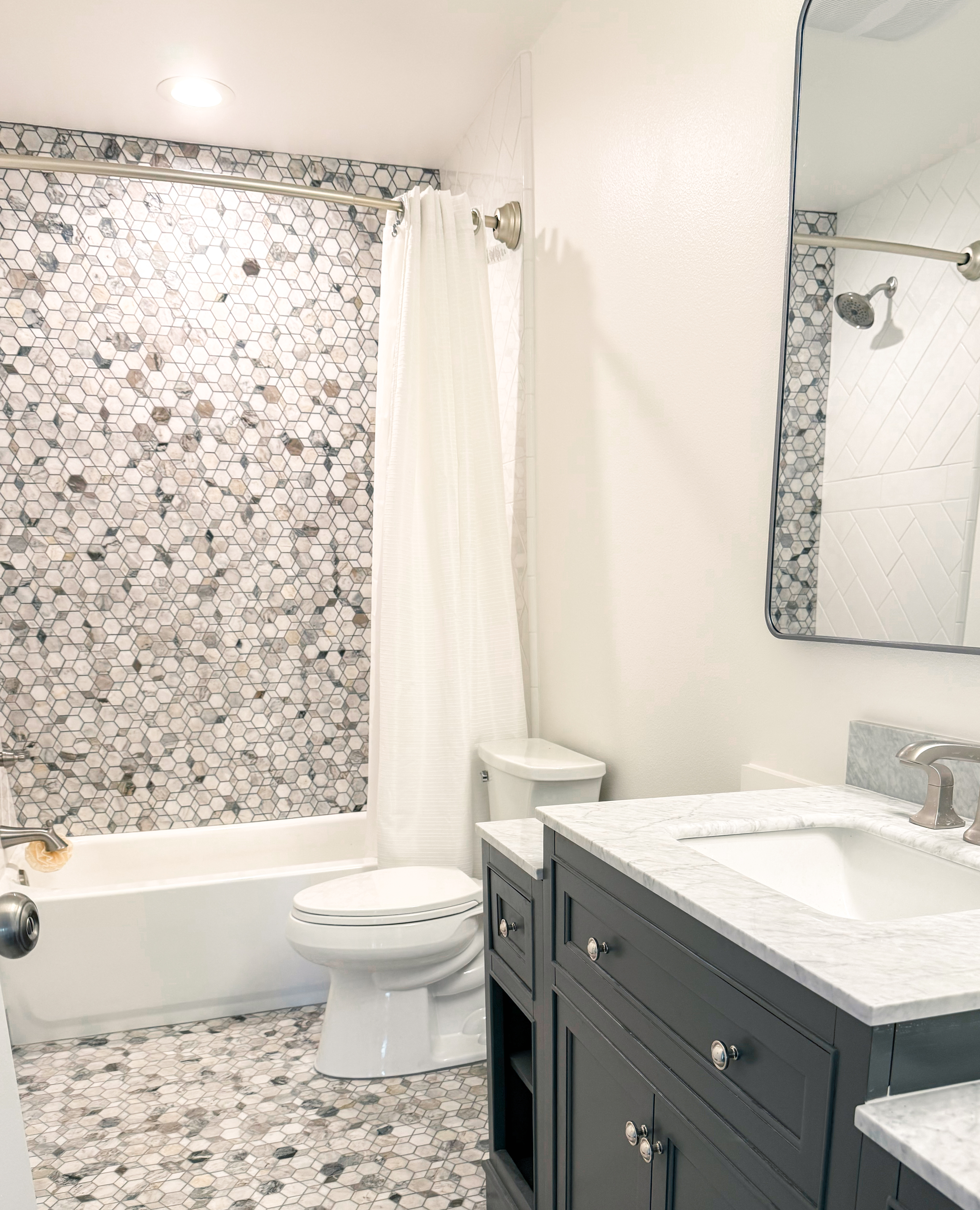 Full bathroom with tile shower wall and granite vanity.