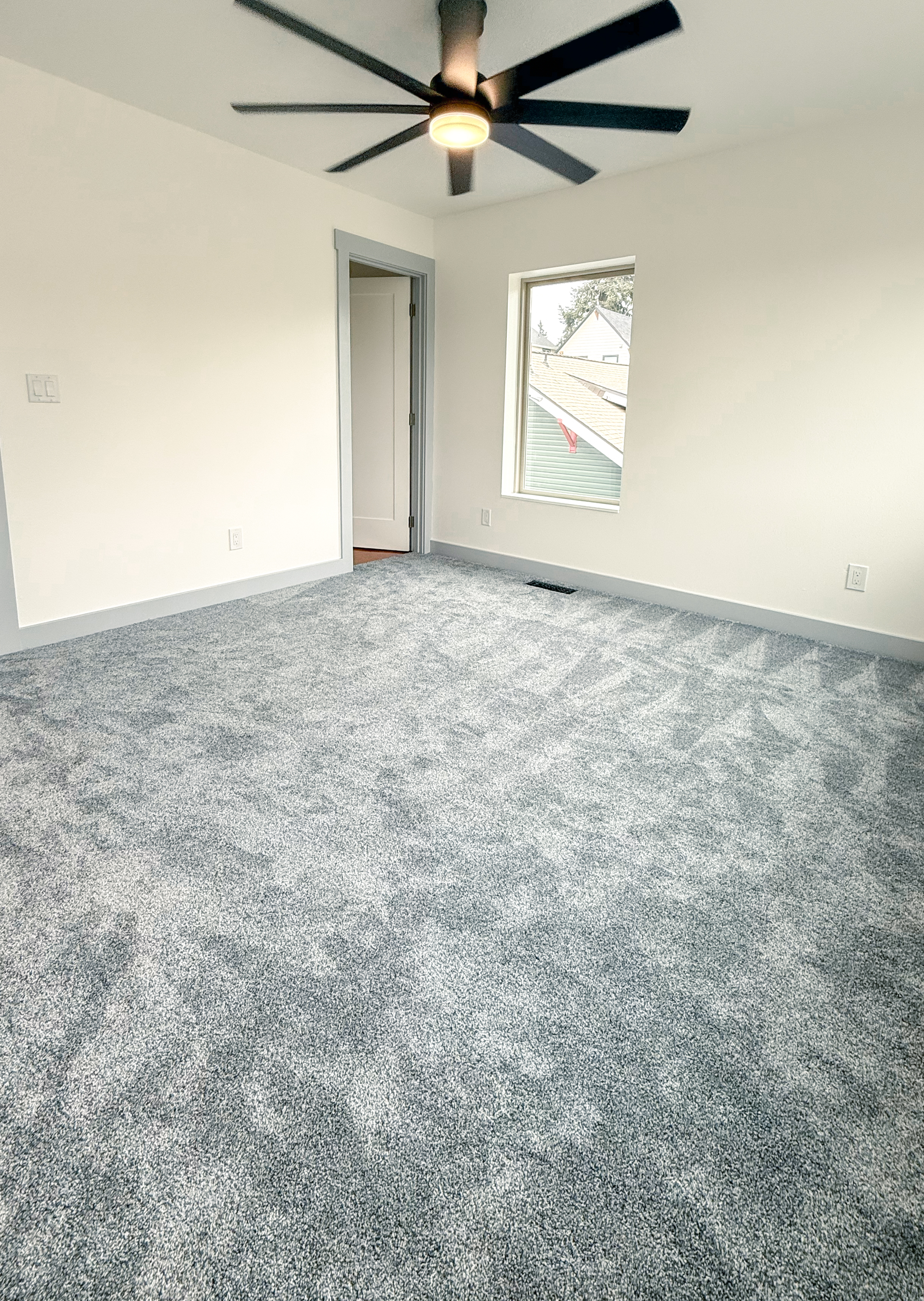 Primary bedroom with carpet, ceiling fan, and window.
