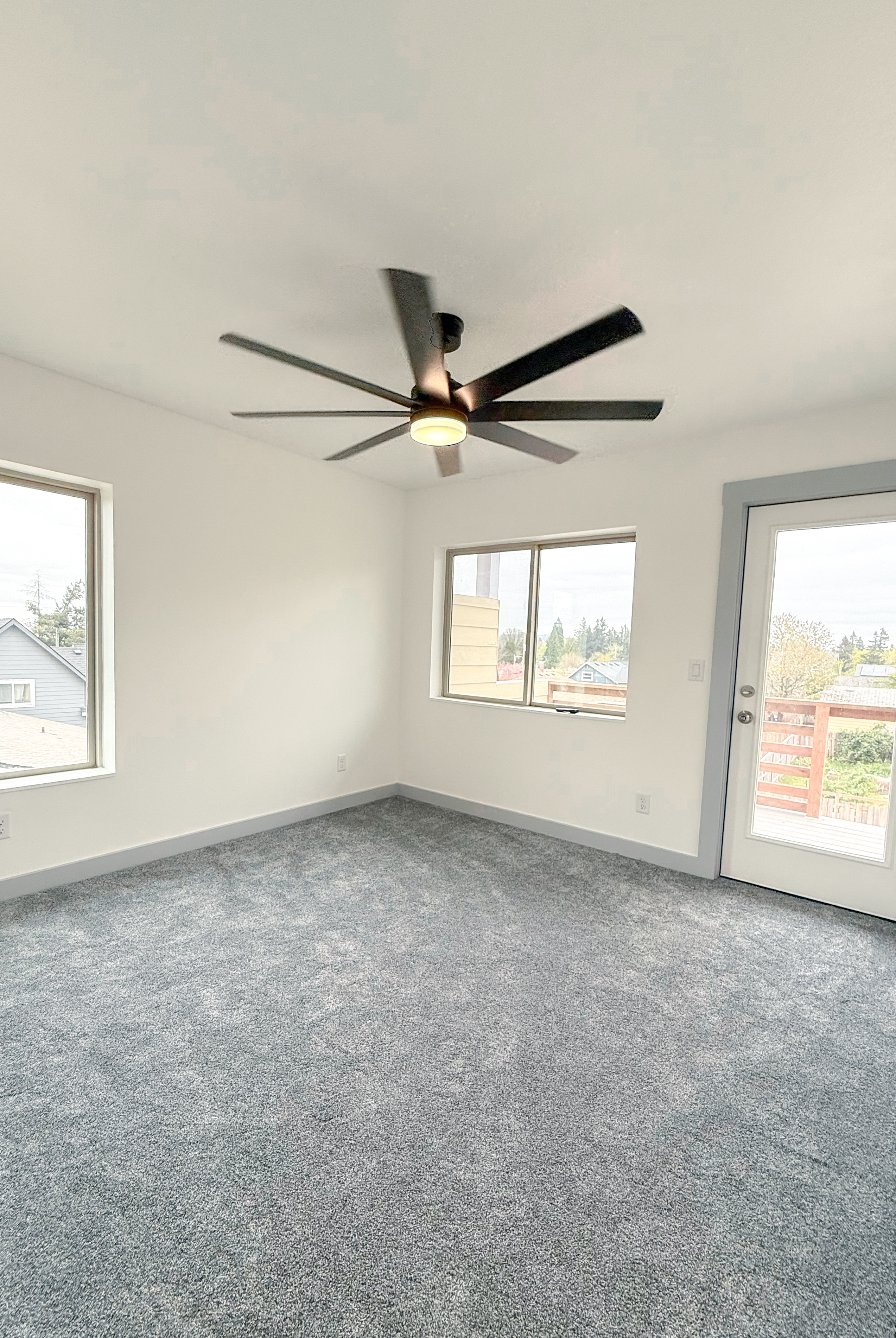 Second bedroom with carpet, windows, and patio door.
